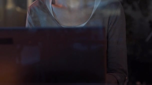 Mujer joven conectándose con su portátil al lado de una ventana — Vídeo de stock