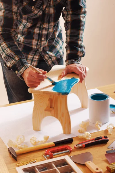 職場のテーブルの上に青いコーティングで家で木製の手作りのスツールを変形職人 — ストック写真