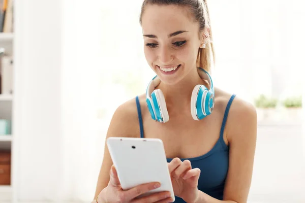快乐运动的女人带着耳机 她正在网上用她的数字平板电脑搜索音乐 — 图库照片
