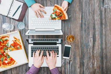 Ofis masasında çalışan iş adamları ve lezzetli bir pizzayla öğle yemeği arası veriyorlar.