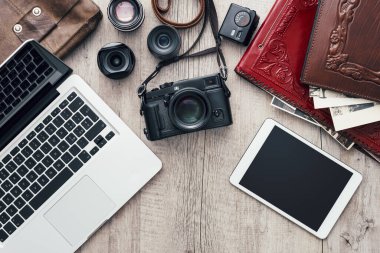 Kaliteli ahşap bir masaüstünde dizüstü bilgisayarı ve dijital tableti olan hippi fotoğraf ekipmanları düz yerde.