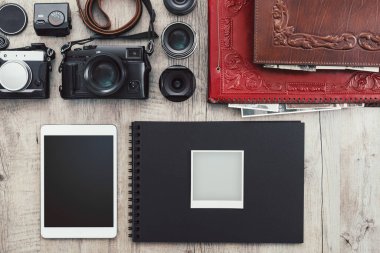 Klasik bir masaüstü, teknoloji ve yaratıcılık kavramında fotoğraf ekipmanları, kameralar, fotoğraf albümü ve dijital tablet