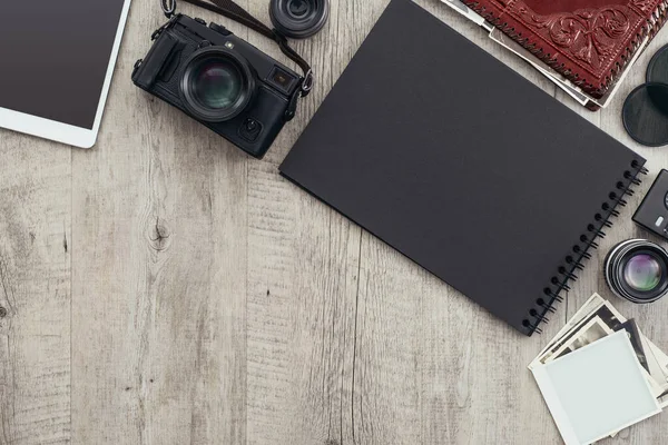 Fotoğraf ekipmanları ve kamera bir masaüstünde, bir fotoğrafçı bir resim tutuyor ve bir fotoğraf albümü yaratıyor
