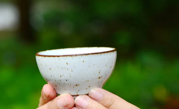녹색 자연 배경으로 인간의 손에 세라믹 차 컵 — 스톡 사진