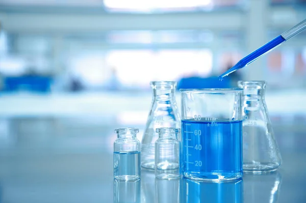 Kropla niebieski do zlewki szklane z kolby i nauki laboratorium — Zdjęcie stockowe