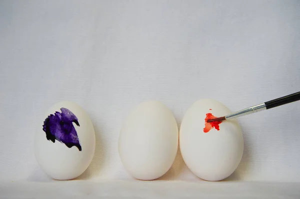 Három húsvéti tojás és a narancs lila ecsettel festék — Stock Fotó