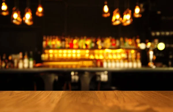 Wood table with blur light of lamp and bar with bottle bacgournd — Stock Photo, Image