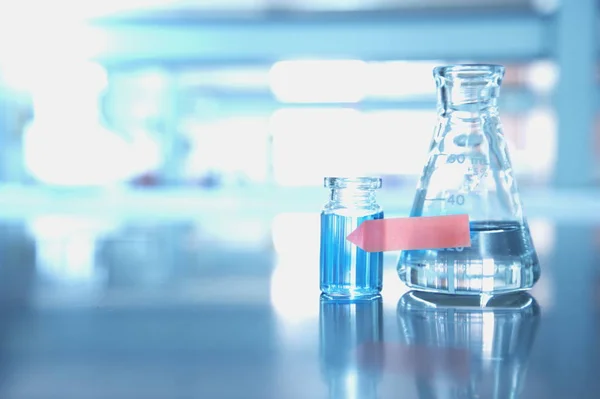 Oranje etiket op de flacon en water in de maatkolf met wetenschap laboratorium — Stockfoto