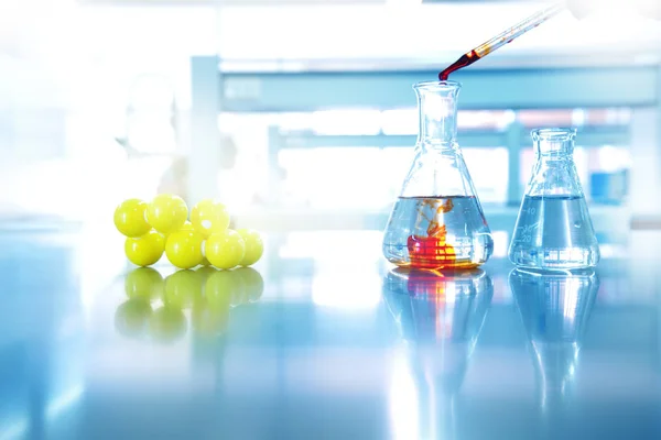 Orange drop solution into water in glass flask with chemical yel — Stock Photo, Image