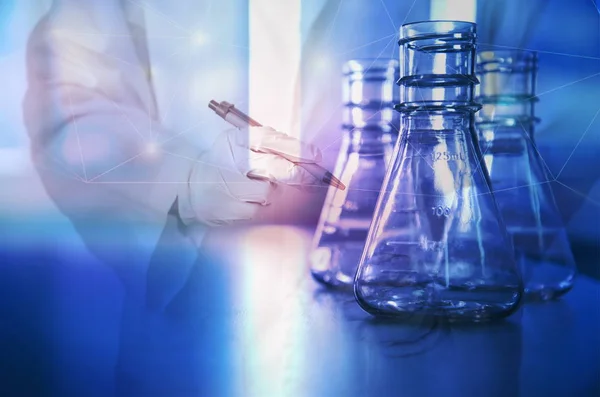 Scientist holding pen with flask in blue science laboratory back — Stock Photo, Image