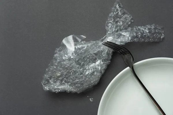 Basura de plástico de pescado con tenedor de metal y plato para comer alimentos en —  Fotos de Stock