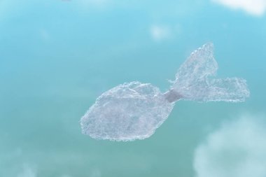 Çevrede mavi su arka planına sahip çöpten gelen plastik balıklar
