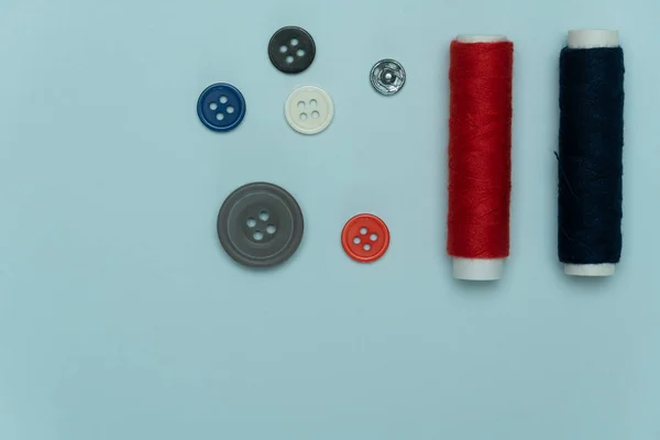 Blue red tread and button for sewing or embroidery on background — 스톡 사진