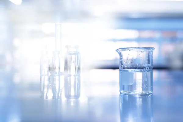 Copo de vidro em azul ciência química laboratório de fundo — Fotografia de Stock