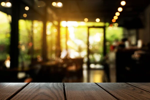 La parte superior de la mesa de madera con luz de noche borrosa en el bar y el restaurante ba —  Fotos de Stock