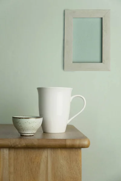 白セラミックマグカップと天然木のテーブルの上のティーカップヴィンテージブルーセメントとグレーの画像フレームの壁フードドリンクや家庭内の背景 — ストック写真