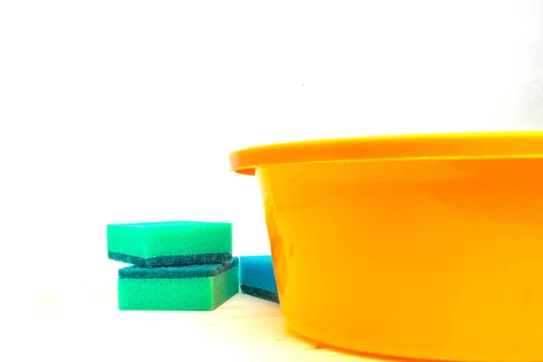 Colorful sponges and an orange basin on a light background.