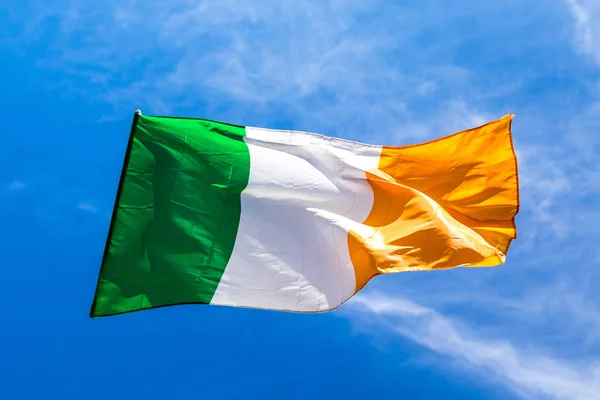 Ír zászló csapkodott a élénk szél ellen egy fényes kék sk — Stock Fotó