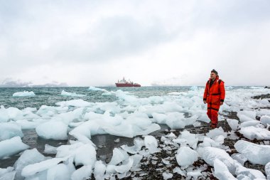 Adam buz ve Antarktika karda yürür. Buzdağları ve her şey etrafında donmuş. Soğuk.