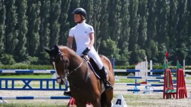 Kadın at sırtında engellerin üzerinden atlar