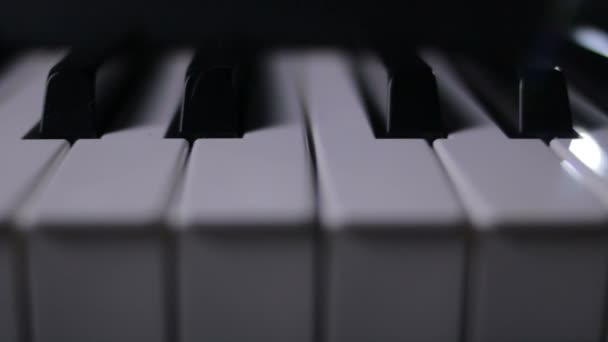 Teclas de piano sobre un fondo oscuro en movimiento — Vídeo de stock