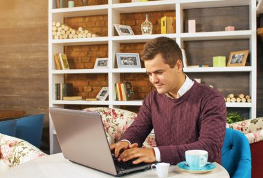 Gülümseyerek mutlu bir genç adam ve onun laptop üzerinde çalışır