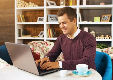 Gülümseyerek mutlu bir genç adam ve onun laptop üzerinde çalışır