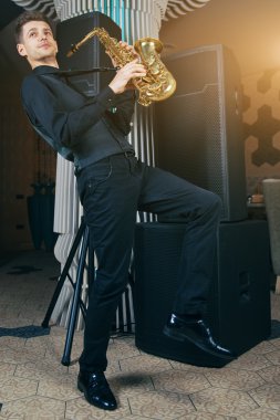 Genç adam bir müzik aleti saksofon çalıyor