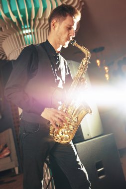 Genç adam bir müzik aleti saksofon çalıyor