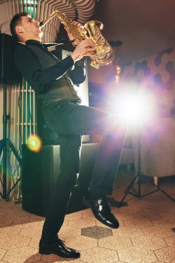 Saksafon üzerinde oynayan takım elbiseli genç adam