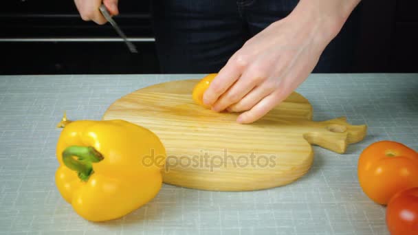 Дівчина з ножем розрізає жовтий помідор — стокове відео