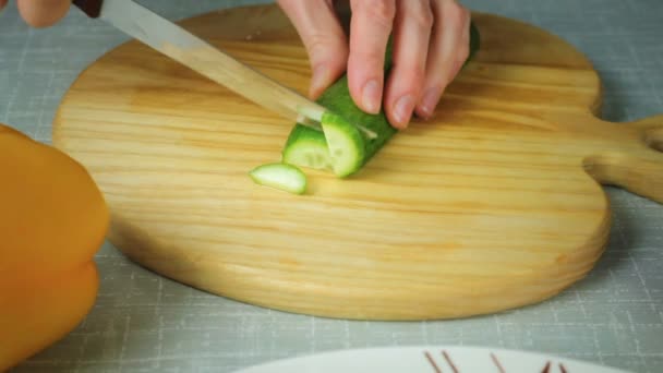 Chica con un cuchillo corta pepino geen — Vídeo de stock