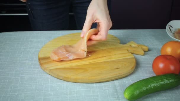 Chica corta un pedazo de pollo crudo — Vídeos de Stock