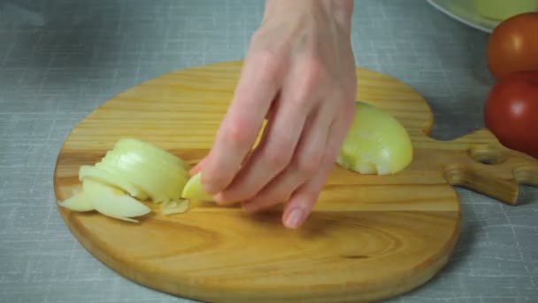 Chef corta un trozo de cebolla amarilla en una tabla de madera — Vídeo de stock