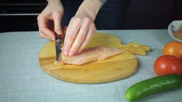 Menina corta um pedaço de frango cru — Vídeo de Stock