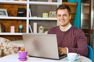 Gülümseyerek mutlu bir genç adam ve onun laptop üzerinde çalışır