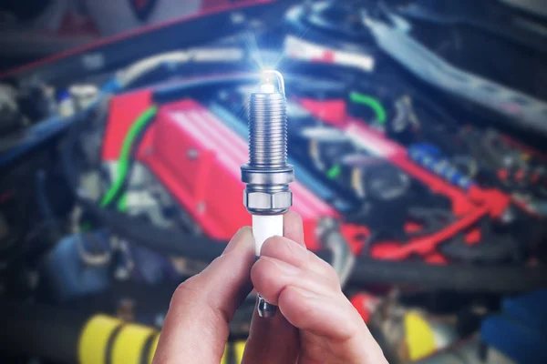 Mechanic holds a spare part spark plug in hand — Stock Photo, Image