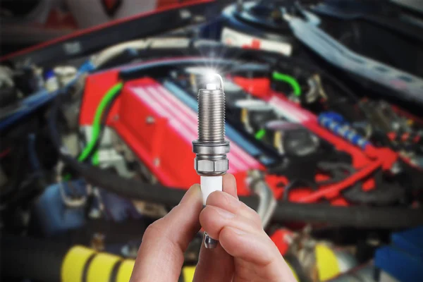 Mechanic holds a spare part spark plug in hand