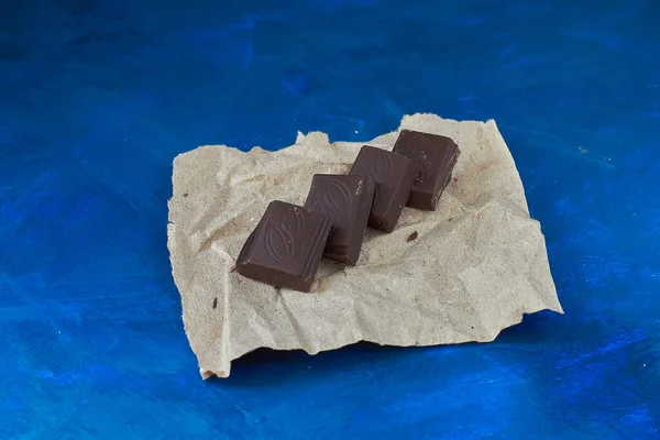 Stücke Dunkler Schokolade Auf Dem Pergament Blauer Hintergrund — Stockfoto