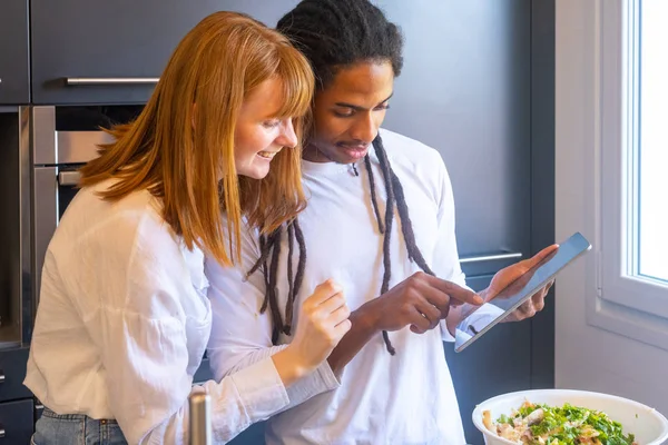 Bir çift mutfaktaki tableti işaret ediyor.
