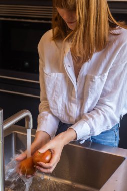 Kızıl saçlı kız domatesleri suyla yıkıyor.