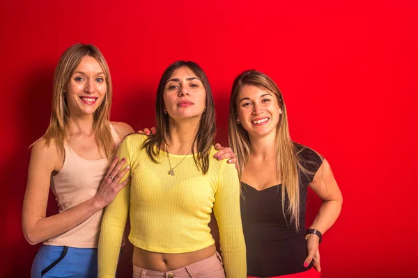 Tre flickor står framför en röd vägg — Stockfoto