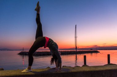 Gün batımında İsviçre 'de Lozan Gölü' nün önünde yoga yapan bir kadın.