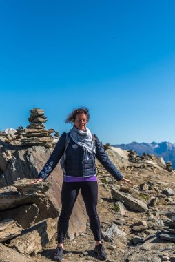 Avuç içleri açık genç bir kadın dünyanın enerjisini arıyor. Taş bir piramidin önünde meditasyon yapmak. Eggishorn terası, enerji ve güç merkezi.