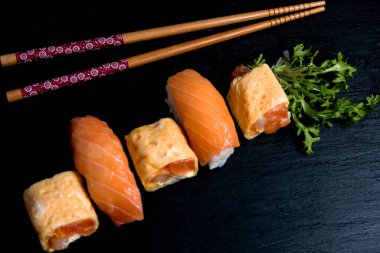 Japon mutfağı nigiri sushi, siyah tabakta wasabi ve soya sosuyla servis edilir. Somonlu suşi, suşi maki rulosu ve siyah tabakta tamago sushi..