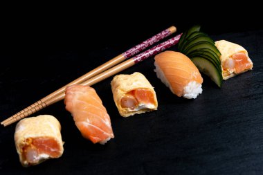 Japon mutfağı nigiri sushi, siyah tabakta wasabi ve soya sosuyla servis edilir. Somonlu suşi, suşi maki rulosu ve siyah tabakta tamago sushi..