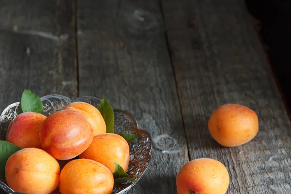 Aprikosen in einer Schüssel auf hölzernem Hintergrund. — Stockfoto