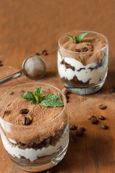 Twee glazen met tiramisu, koffiebonen en muntblaadjes. Donkere achtergrond. Selectieve aandacht. — Stockfoto