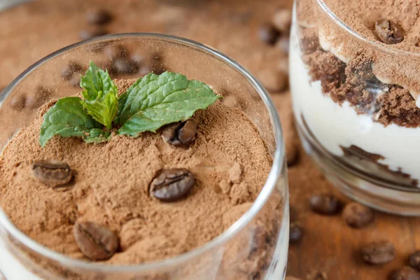 Dos vasos con tiramisú, granos de café y hojas de menta. Fondo oscuro. Enfoque selectivo . —  Fotos de Stock