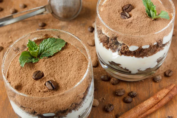 Dos vasos con tiramisú, granos de café y hojas de menta. Fondo oscuro. Enfoque selectivo . —  Fotos de Stock